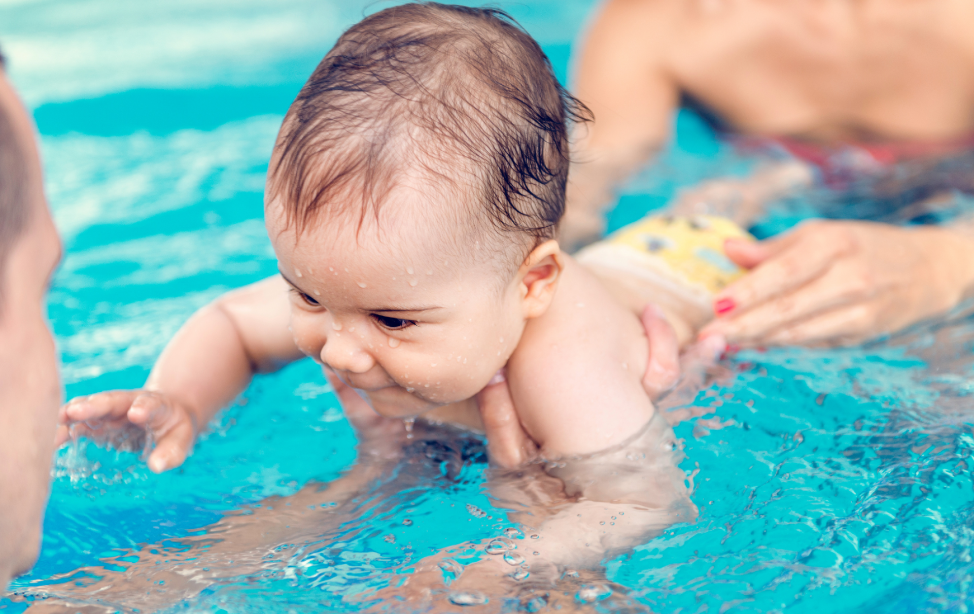 Baby mit Eltern beim Babyschwimmen