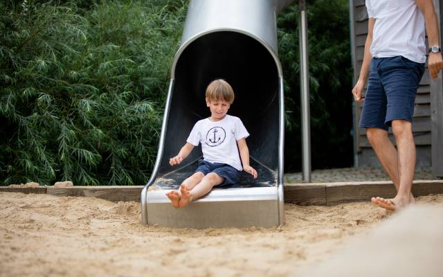 Junge beim Rutschen auf dem Abenteuerspielplatz 